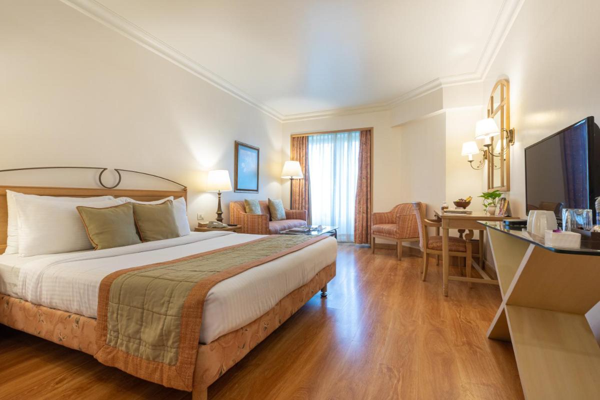 a hotel room with a bed and a desk at The Orchid Hotel Mumbai Vile Parle in Mumbai
