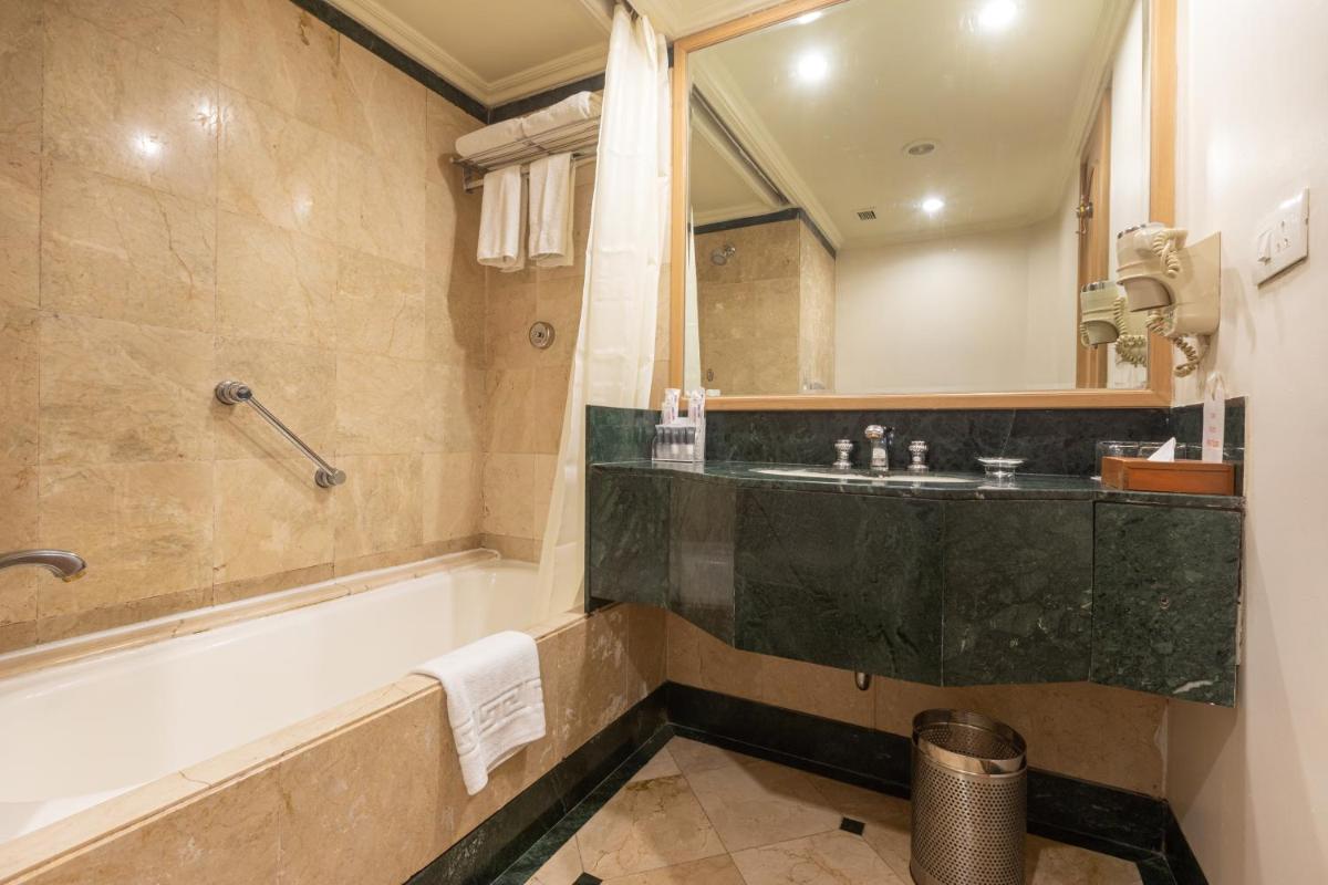 a bathroom with a tub and a sink and a mirror at The Orchid Hotel Mumbai Vile Parle in Mumbai