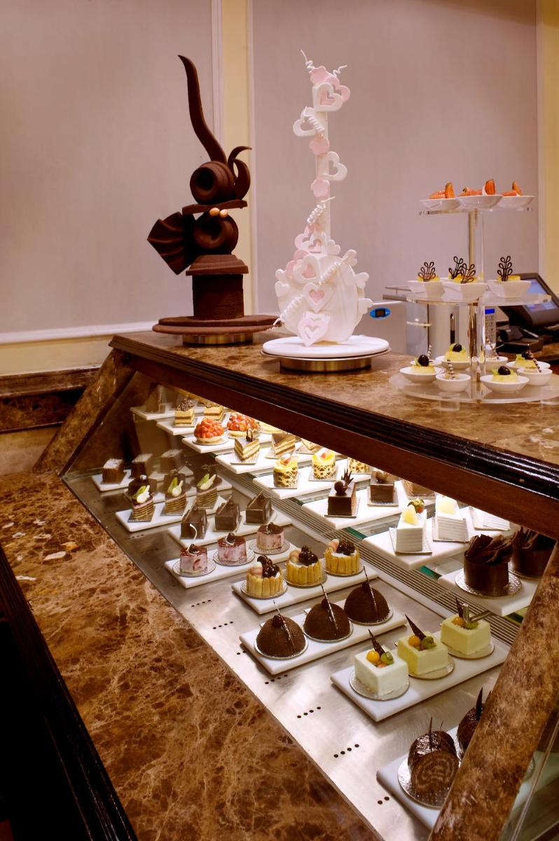 a display case filled with lots of different types of desserts at The Suryaa New Delhi in New Delhi a display case filled with lots of different types of desserts at The Suryaa New Delhi in New Delhi