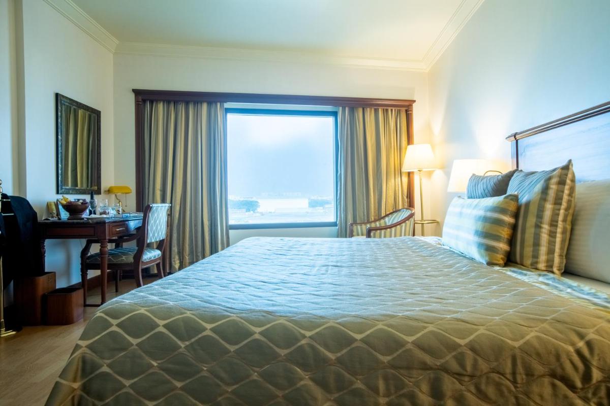 a hotel room with a bed and a desk and a window at The Orchid Hotel Mumbai Vile Parle in Mumbai