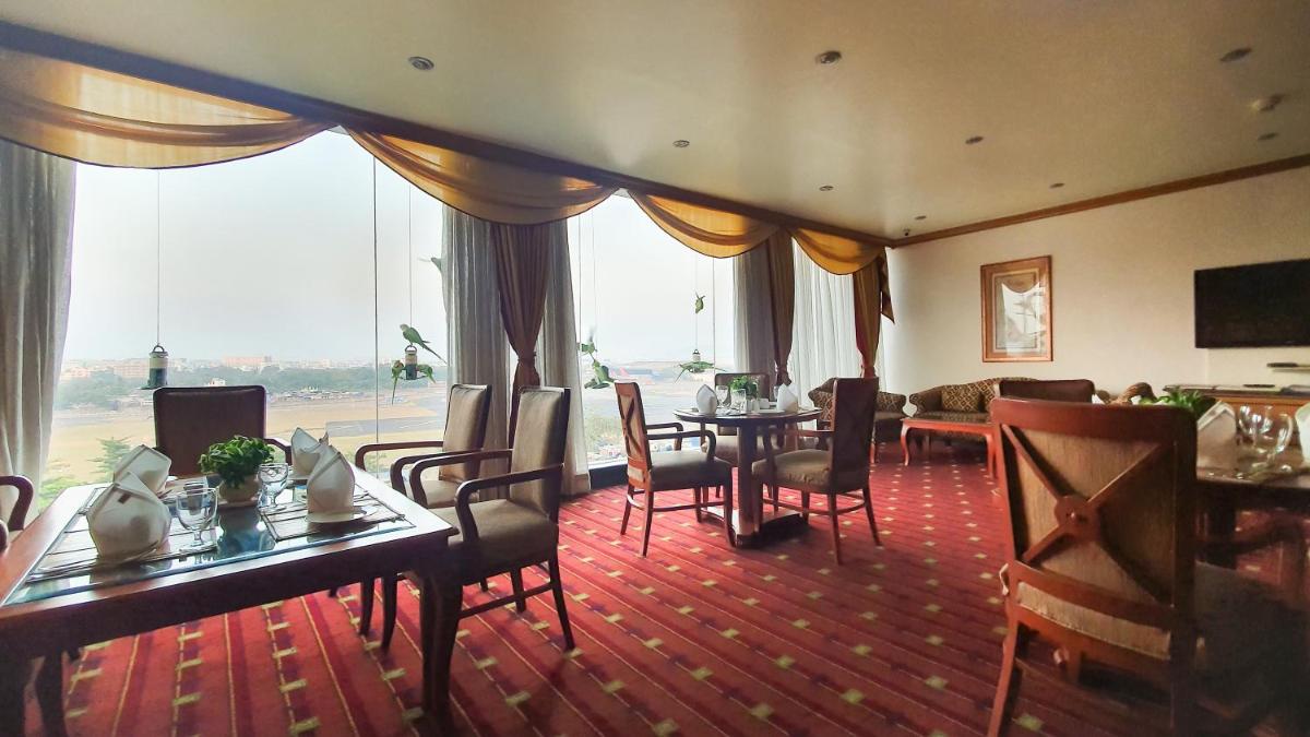 a hotel room with tables and chairs and a large window at The Orchid Hotel Mumbai Vile Parle in Mumbai