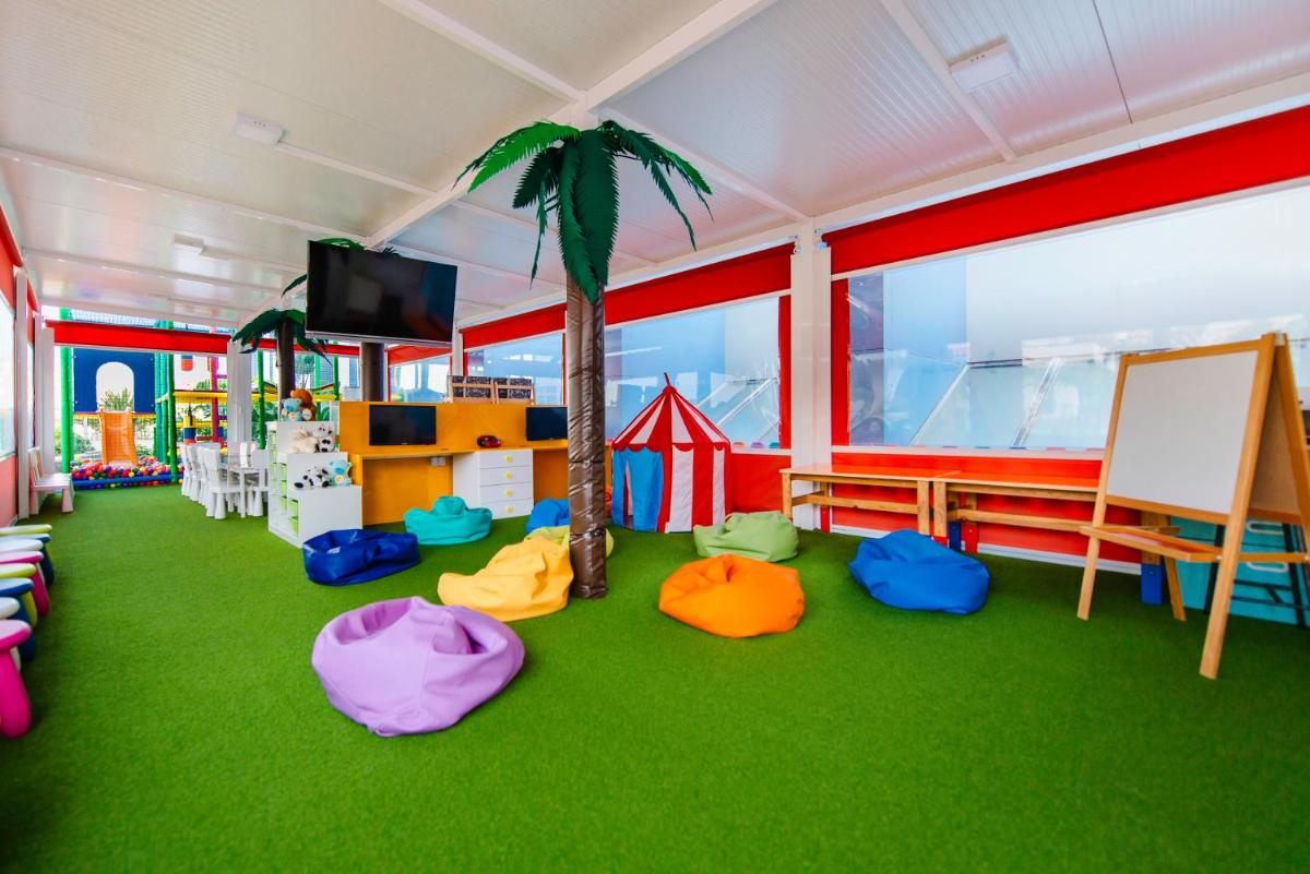 Una habitación con una palmera y una zona de juegos. en Paradise Park Fun Lifestyle Hotel, en Los Cristianos