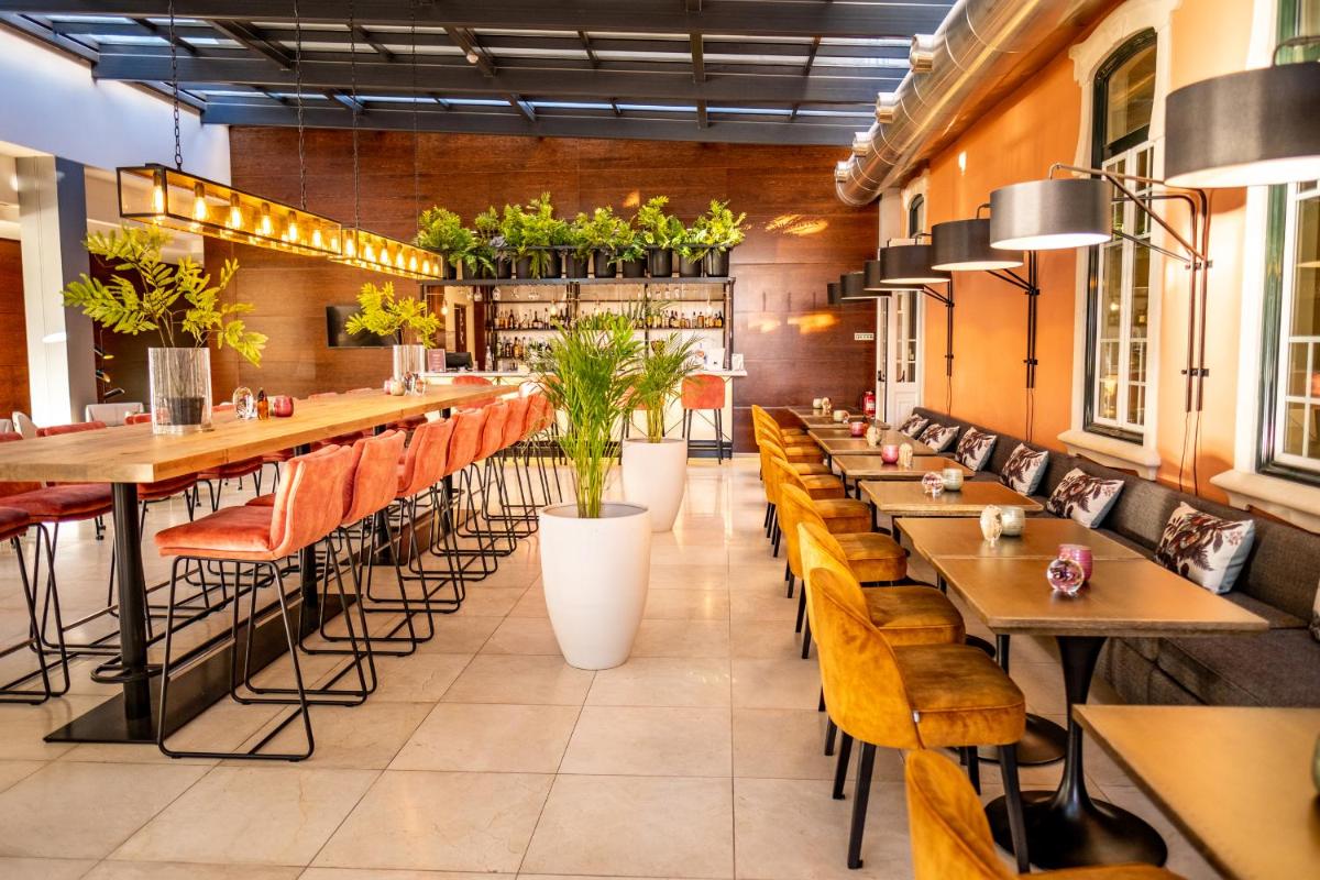um restaurante com mesas de madeira, cadeiras e plantas em Monte Real - Hotel, Termas & Spa em Monte Real