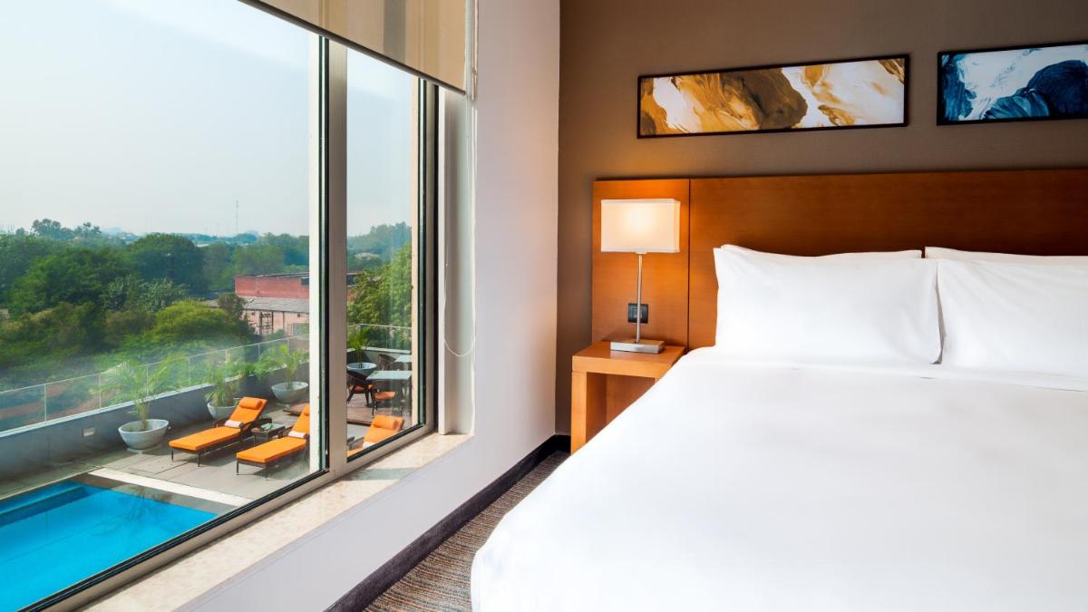 a hotel room with a bed and a large window at Hyatt Place Gurgaon Udyog Vihar in Gurgaon