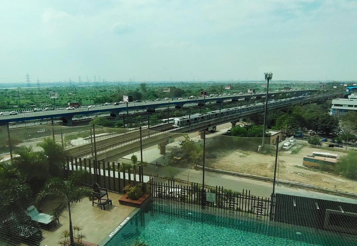 a train is crossing a bridge over a road at Crowne Plaza New Delhi Mayur Vihar Noida by IHG in New Delhi