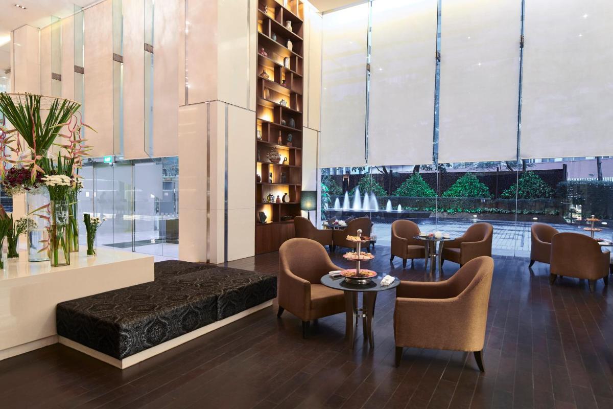 a hotel lobby with chairs and tables and windows at Holiday Inn Mumbai International Airport by IHG in Mumbai
