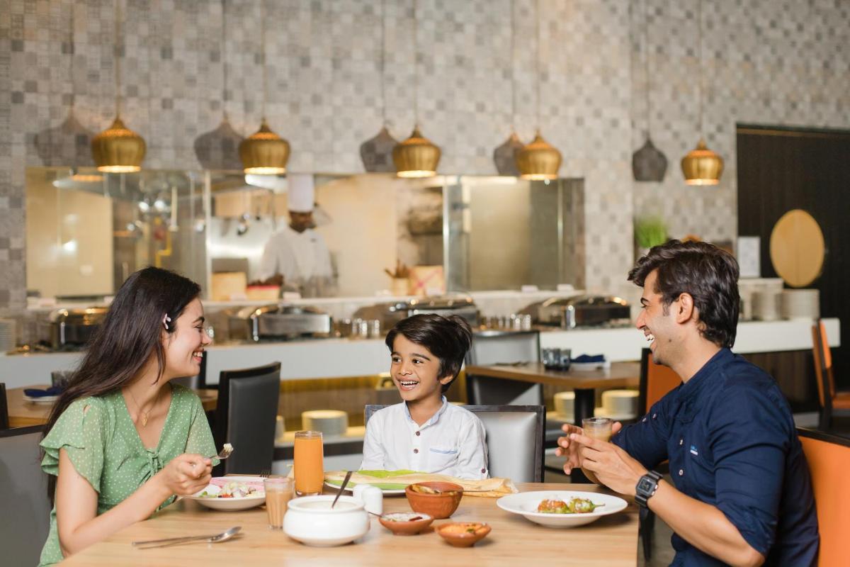 a group of people sitting at a table eating food at The Residency Towers, Rameswaram in Rāmeswaram