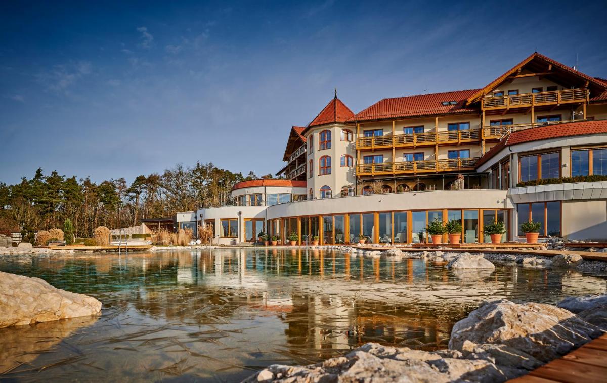 ein Resort mit einem Teich vor einem Gebäude in der Unterkunft Der Birkenhof Spa & Genuss Resort in Hofenstetten