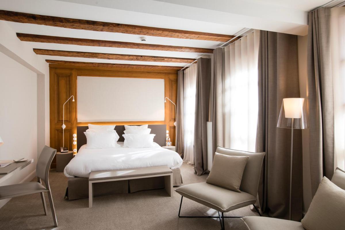 une chambre d'hôtel avec un lit et une chaise dans l'établissement Relais & Châteaux La Maison Des Têtes, à Colmar
