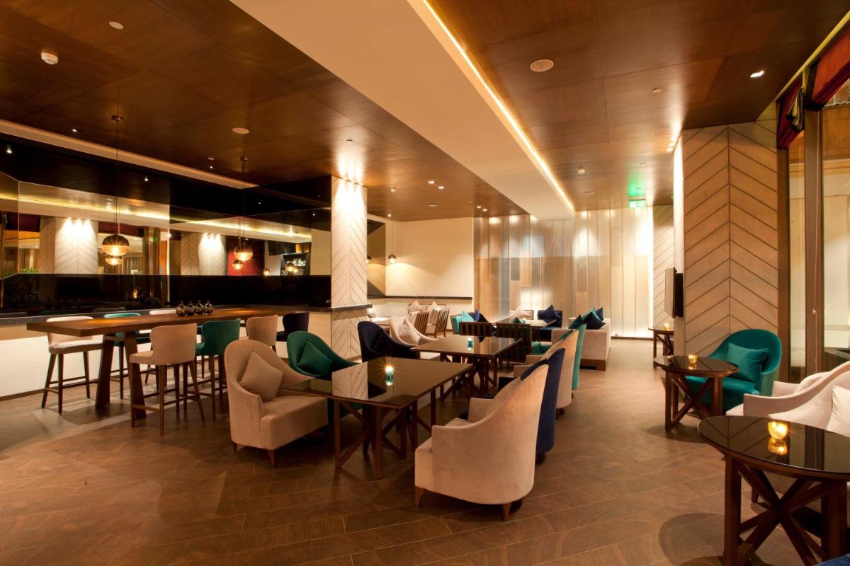 a restaurant with tables and chairs and a bar at Hyatt Regency Amritsar Hotel & Spa in Amritsar