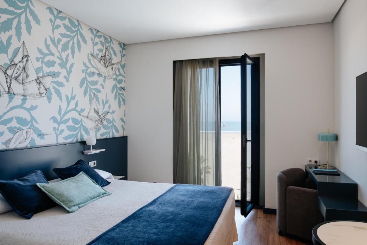 Un dormitorio con una cama y un sofá y una ventana. en Hotel Neptuno Playa & Spa, en Valencia