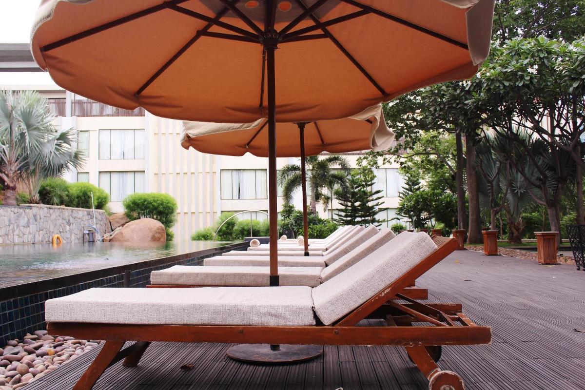 a row of lounge chairs with an umbrella at Hyatt Hyderabad Gachibowli in Hyderabad
