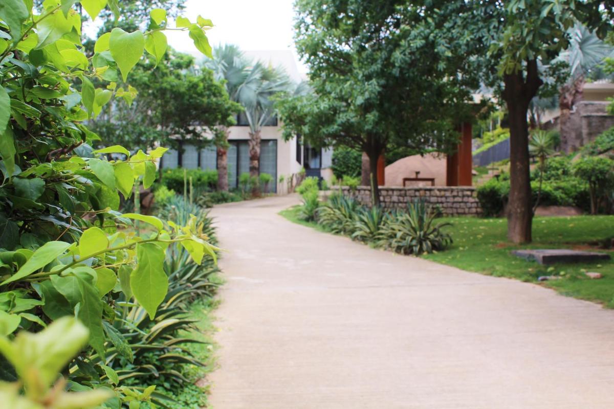 a path in a park with trees and a bench at Hyatt Hyderabad Gachibowli in Hyderabad