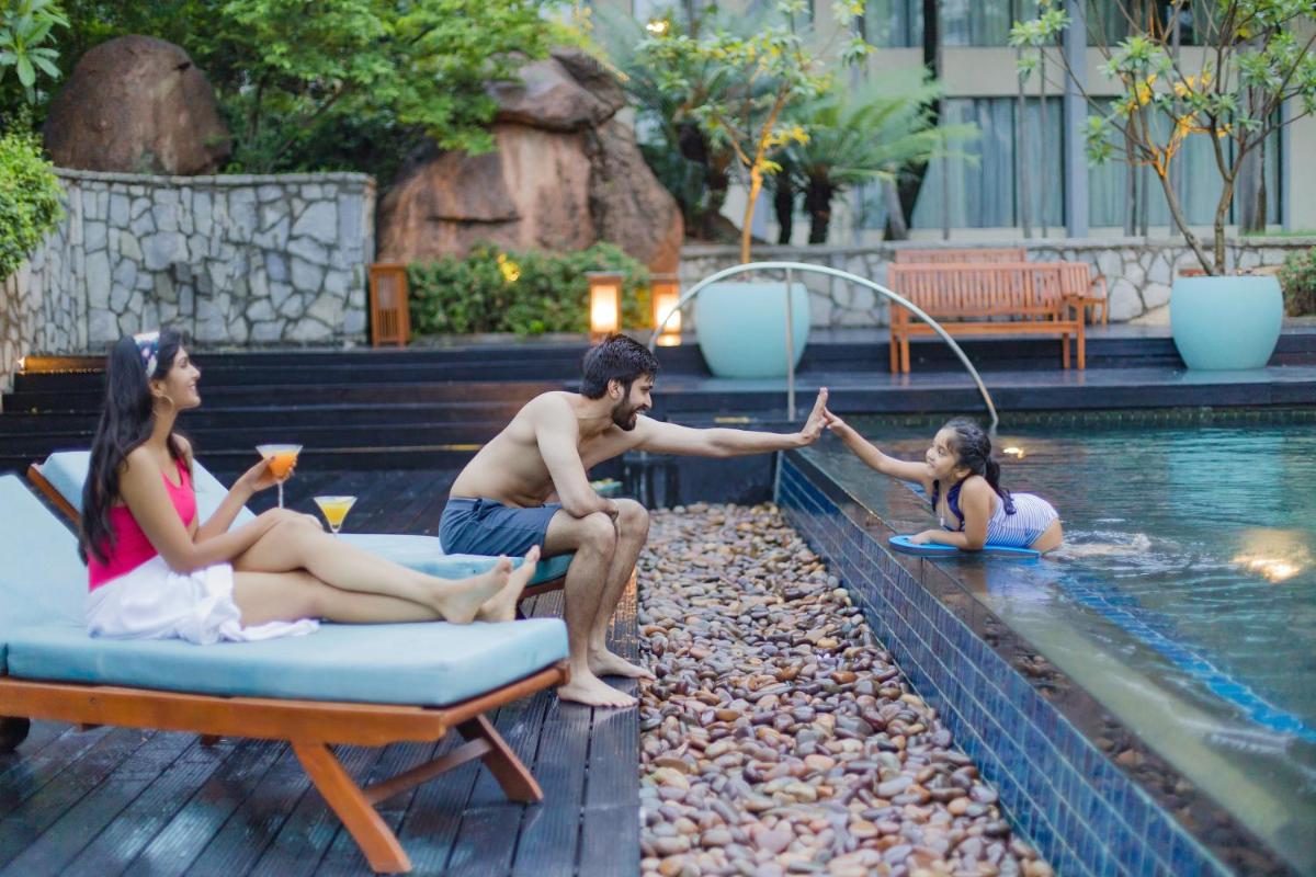 a group of people sitting around a swimming pool at Hyatt Hyderabad Gachibowli in Hyderabad