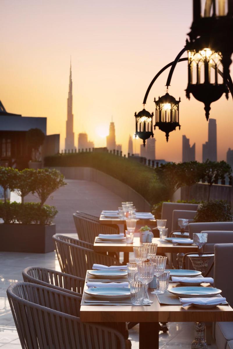 a table with plates and wine glasses in front of a city at Barcelo Al Jaddaf, Dubai in Dubai