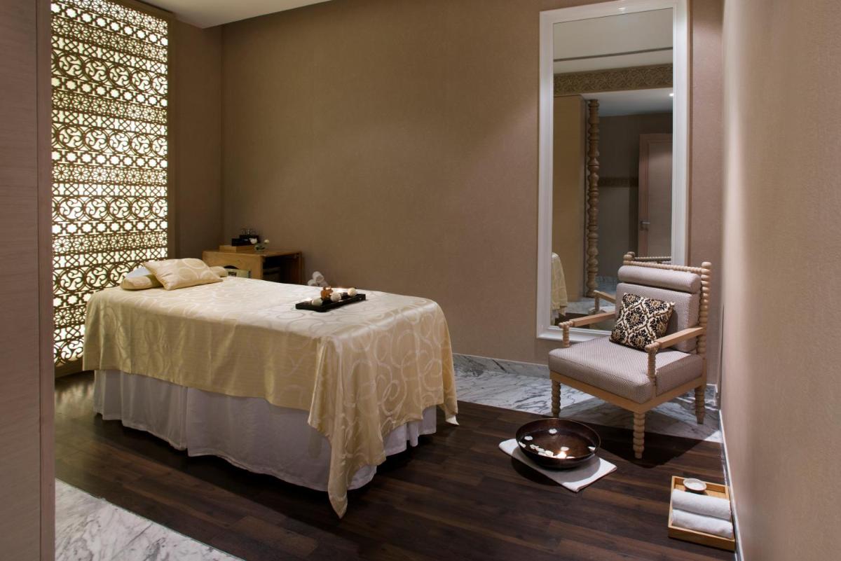 a bedroom with a bed and a chair and a mirror at Hyatt Regency Gurgaon in Gurgaon