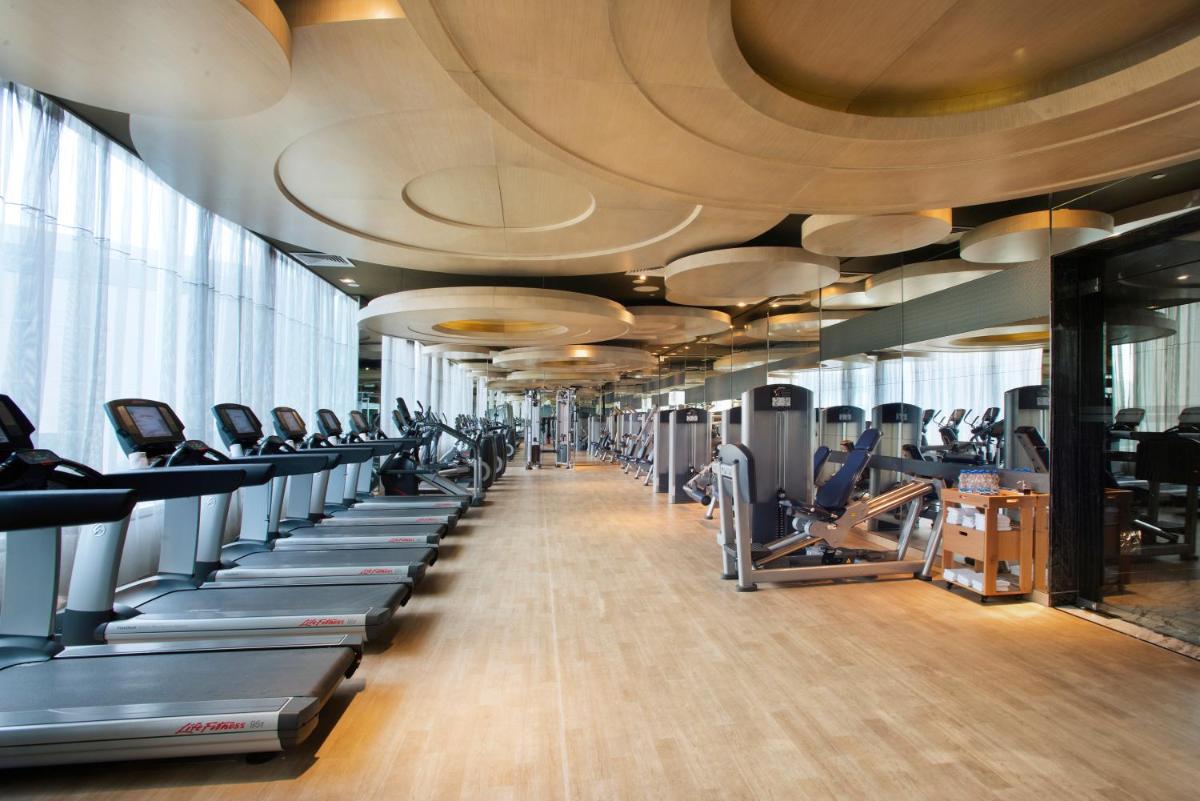 a gym with a row of treadms and machines at Hyatt Regency Gurgaon in Gurgaon