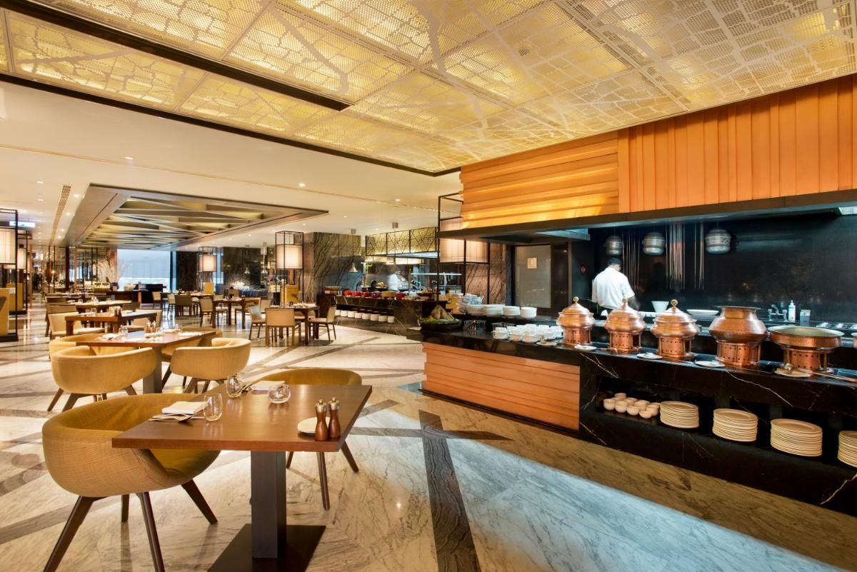 a restaurant with tables and chairs and a counter at Hyatt Regency Gurgaon in Gurgaon a restaurant with tables and chairs and a counter at Hyatt Regency Gurgaon in Gurgaon
