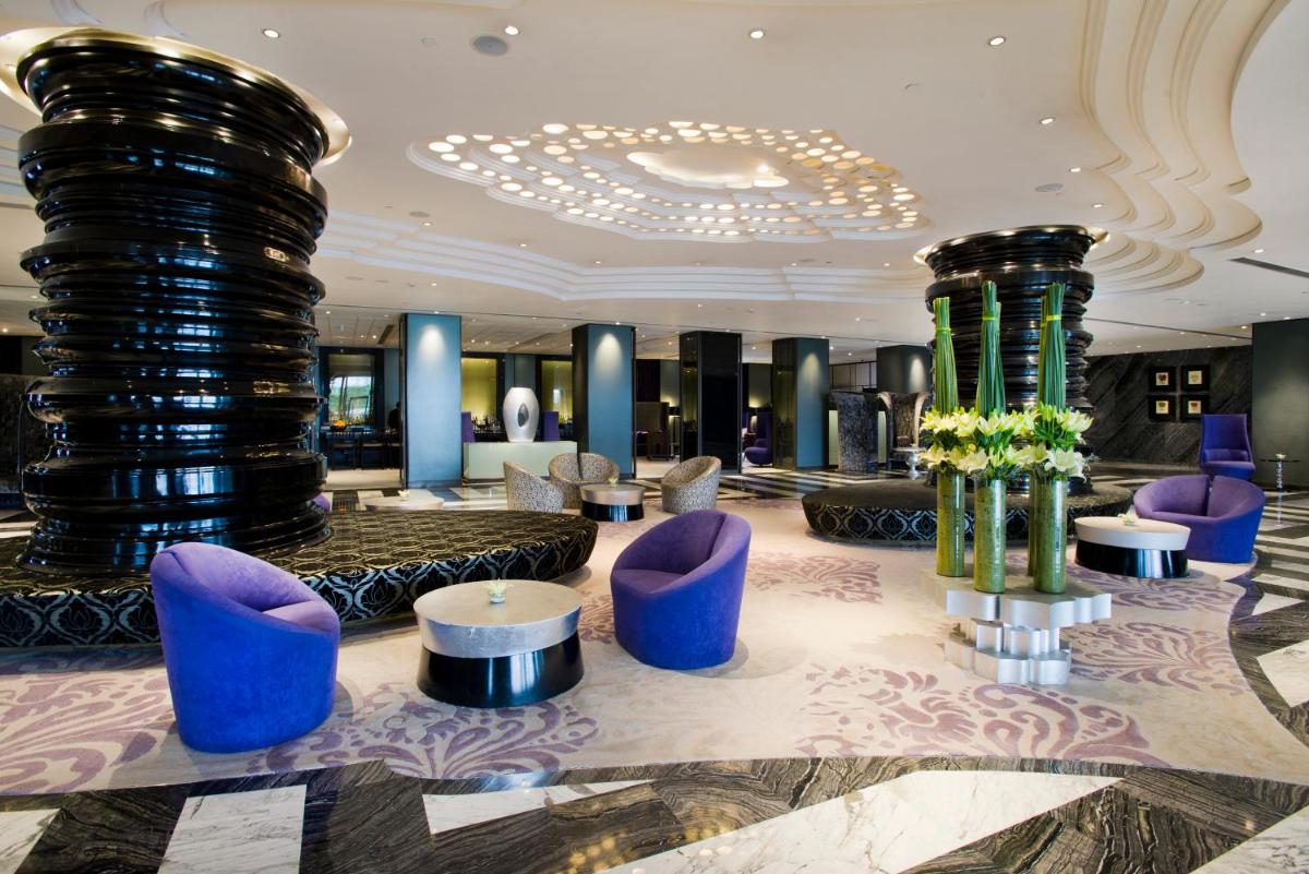 a lobby with purple chairs and tables and a chandelier at Hyatt Regency Gurgaon in Gurgaon