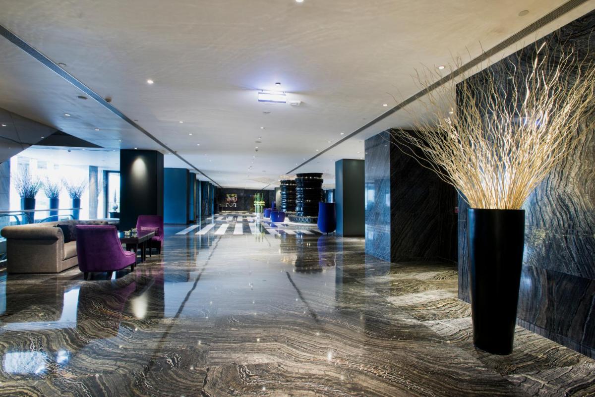 a hallway with a lobby with purple chairs and a vase at Hyatt Regency Gurgaon in Gurgaon