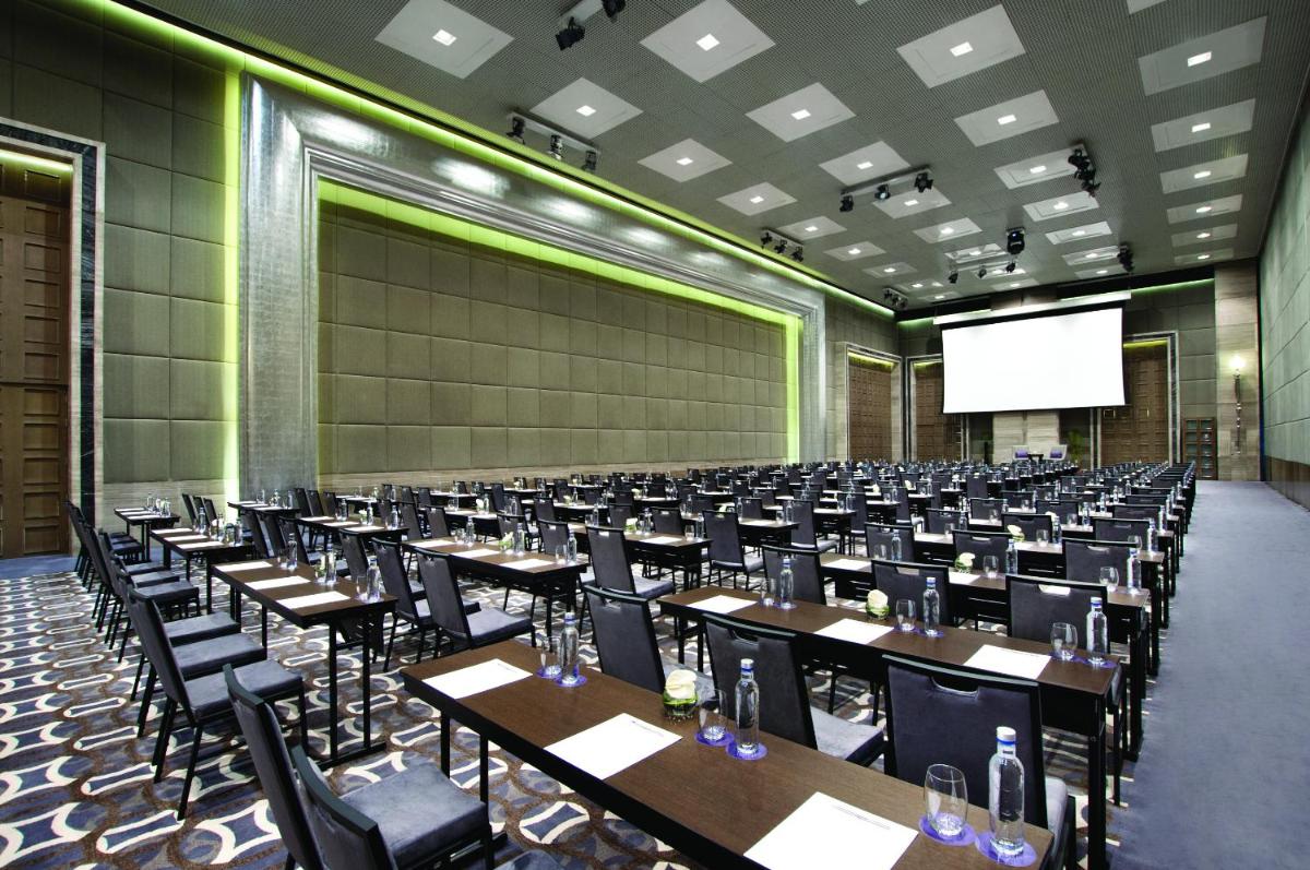 a conference room with tables and chairs and a screen at Hyatt Regency Gurgaon in Gurgaon