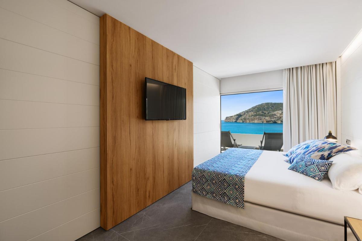 Una habitación de hotel con una cama y un televisor de pantalla plana. en Bahia Suites Camp de Mar, en Camp de Mar