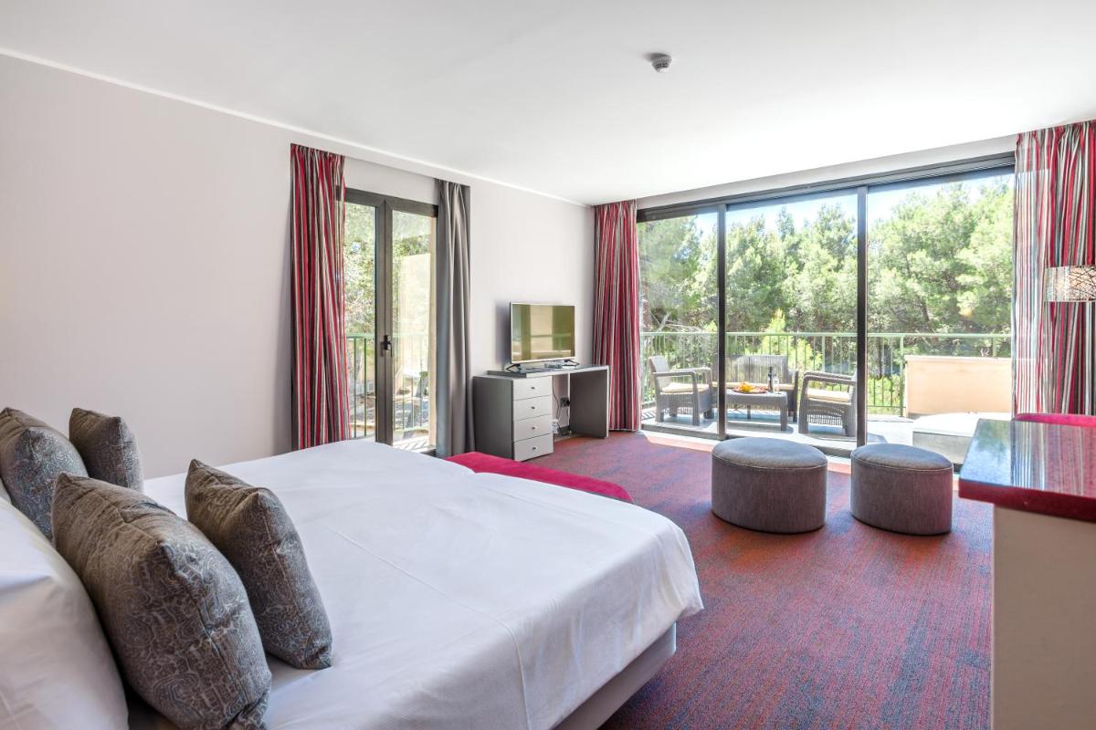 Un dormitorio con una cama y una ventana grande. en Lago Garden Apart-Suites & Spa Hotel, en Cala Ratjada