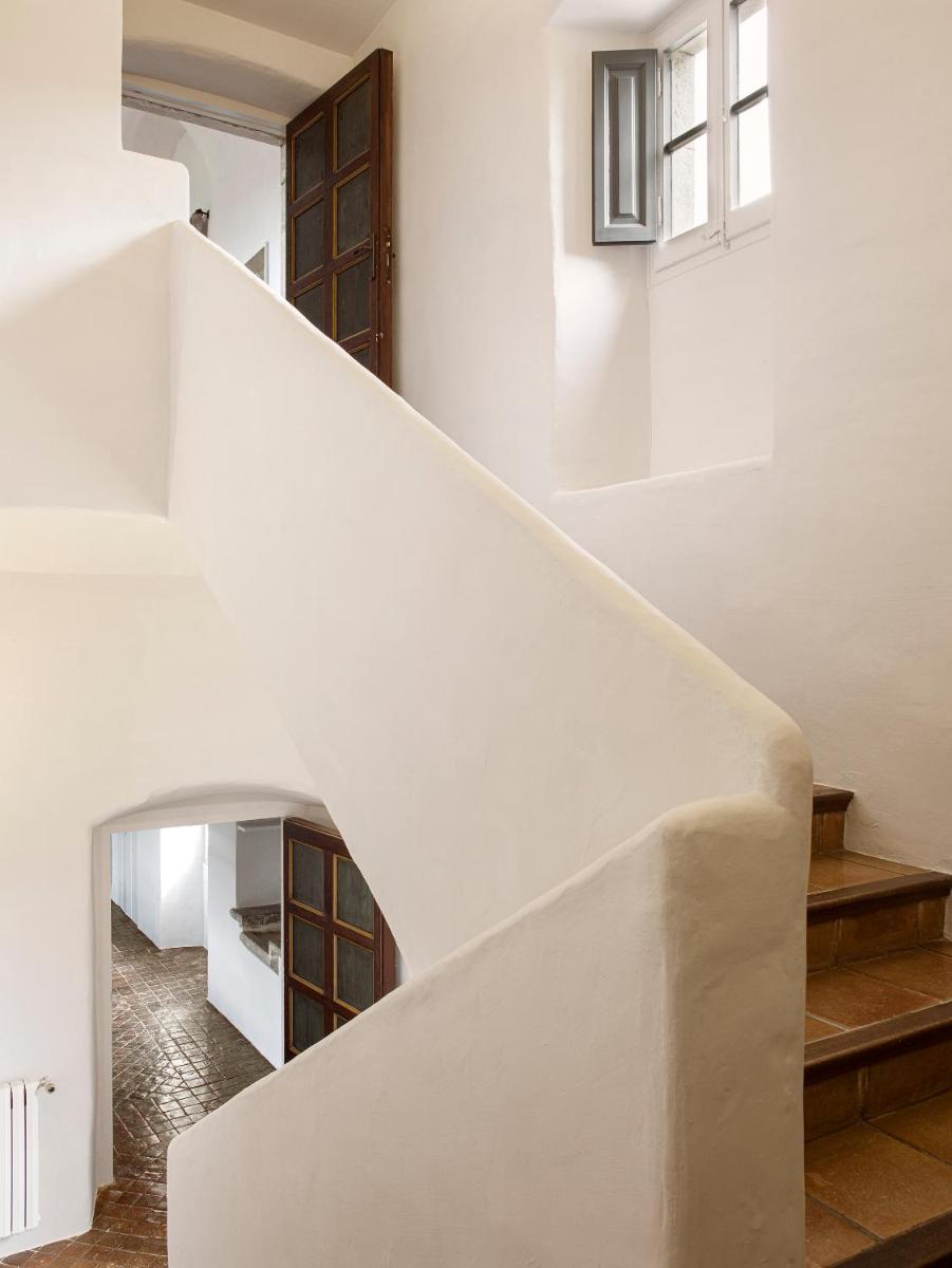 una escalera en una casa con paredes blancas en Mas de Torrent Hotel & Spa, Relais & Châteaux, en Torrent