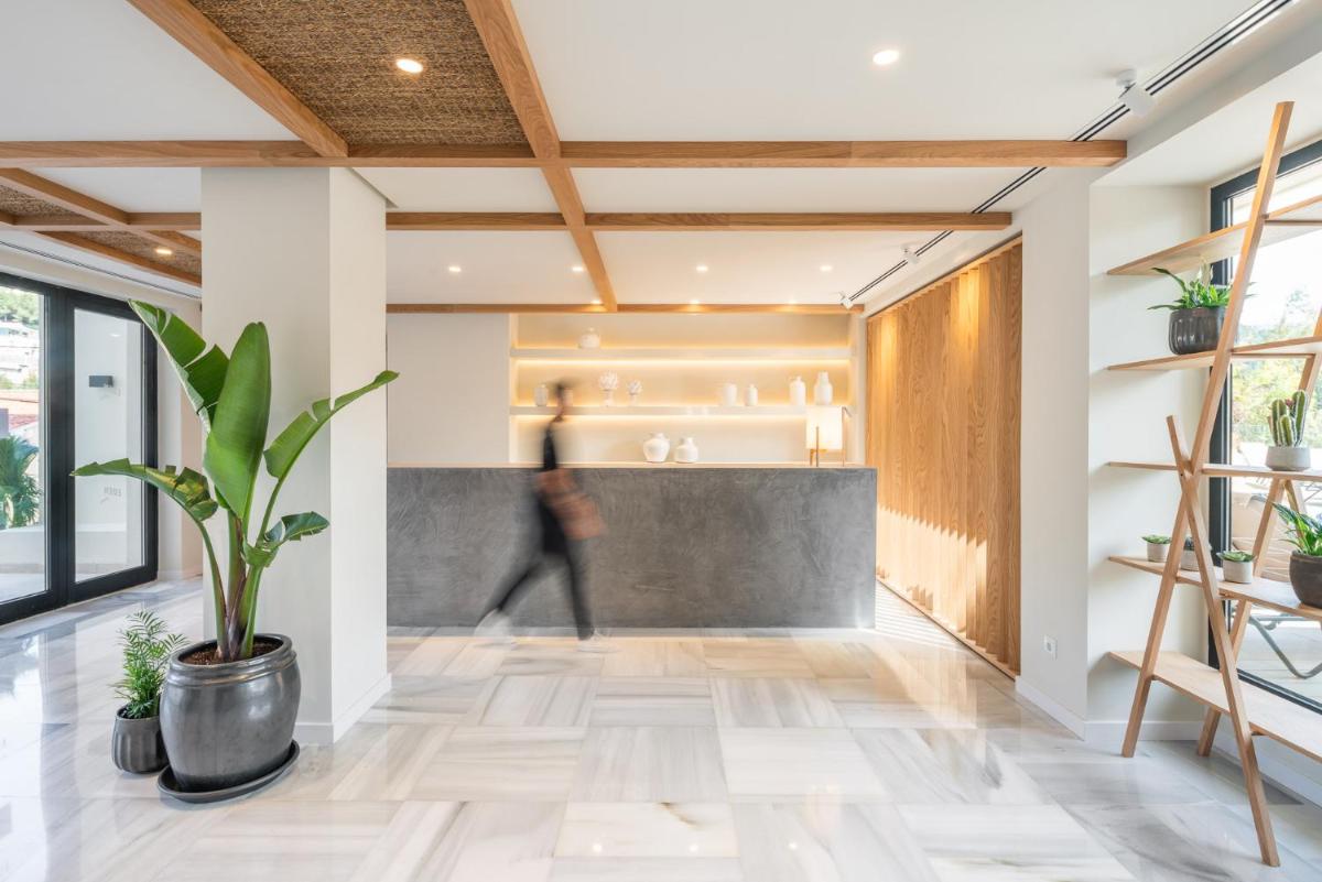 Una persona caminando por un vestíbulo con una planta. en Hotel Eden Nord Soller, en Puerto de Sóller