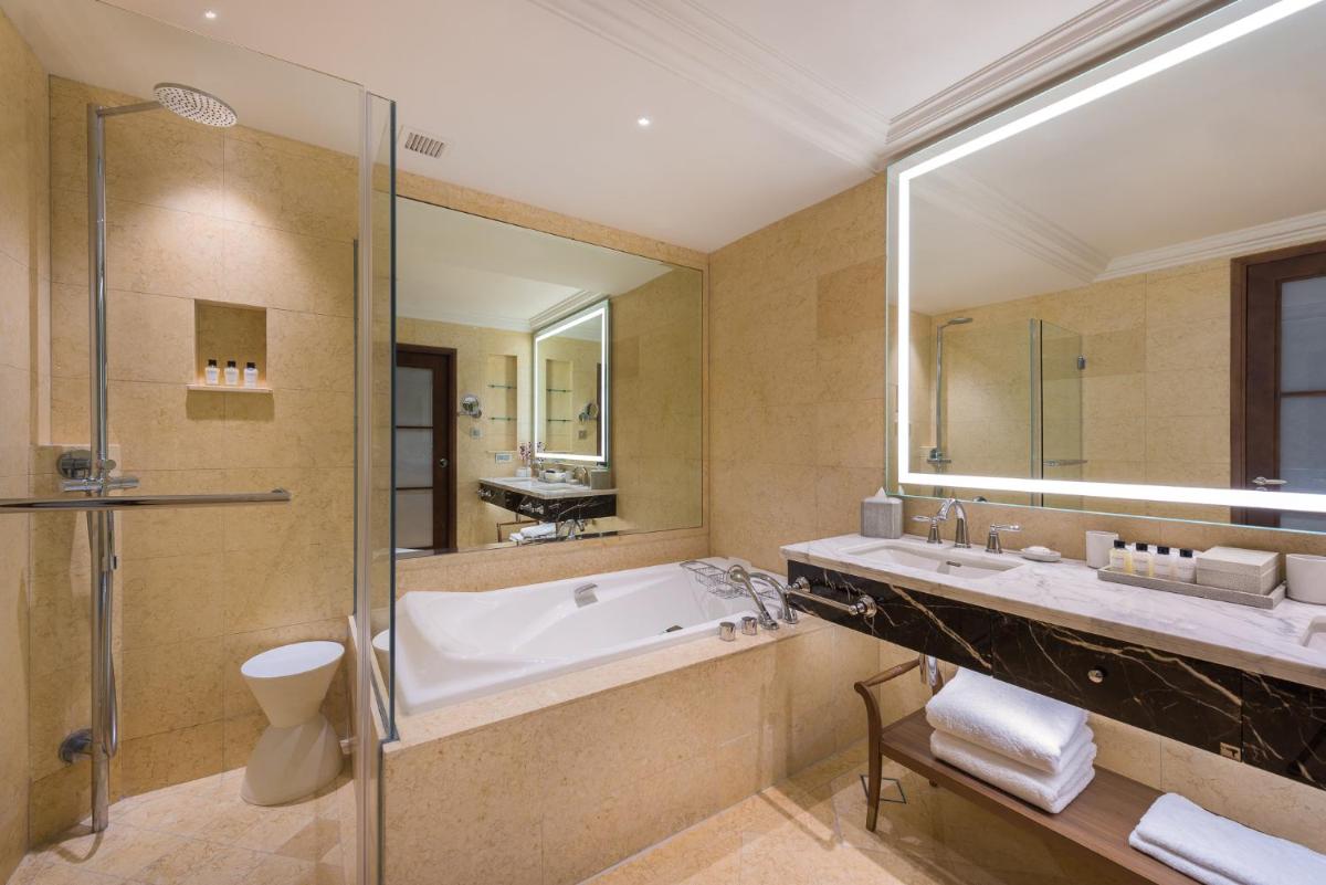 a bathroom with a tub and a large mirror at The Fullerton Hotel Singapore in Singapore