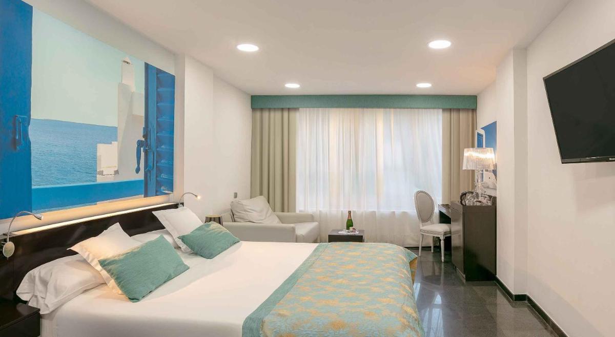 Un dormitorio con una cama grande y una sala de estar. en Hotel Villa del Mar, en Benidorm