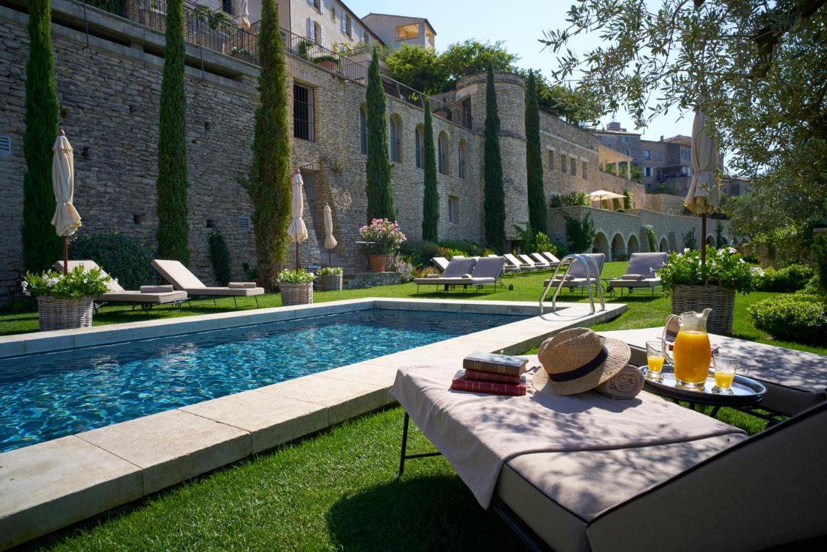 une piscine dans une cour avec une table et des chaises dans l'établissement Airelles Gordes, La Bastide, à Gordes