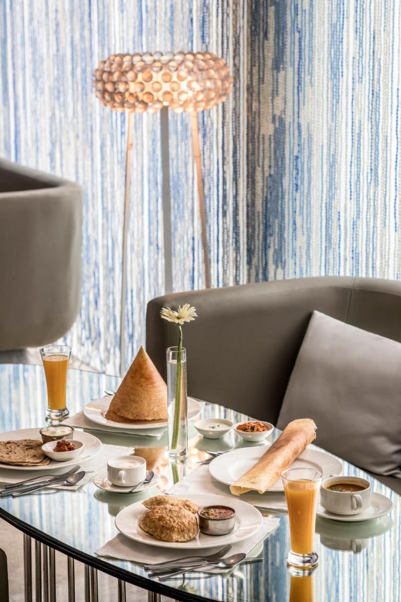 a glass table with plates of food on it at The Park New Delhi in New Delhi a glass table with plates of food on it at The Park New Delhi in New Delhi