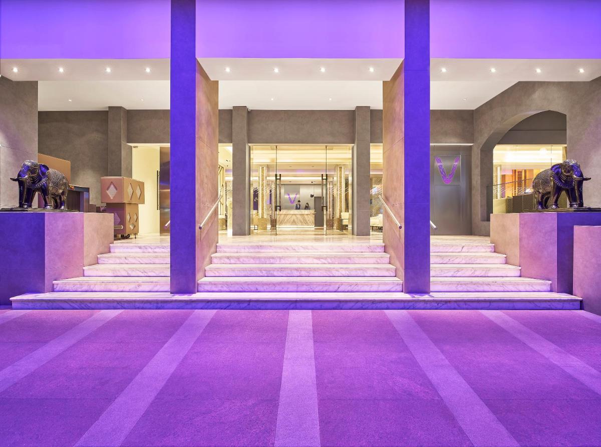 a lobby with purple columns and stairs with statues at Vivanta Bengaluru Residency Road in Bengaluru a lobby with purple columns and stairs with statues at Vivanta Bengaluru Residency Road in Bengaluru