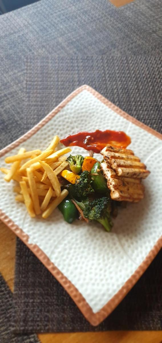 a plate of food with fries and broccoli and ketchup at Antalya By Divine Ganga Cottage in Rishīkesh