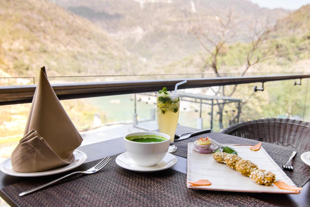 a table with a drink and a plate of food at Antalya By Divine Ganga Cottage in Rishīkesh