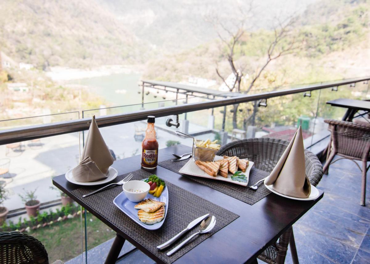 a table with a plate of food and a bottle of beer at Antalya By Divine Ganga Cottage in Rishīkesh
