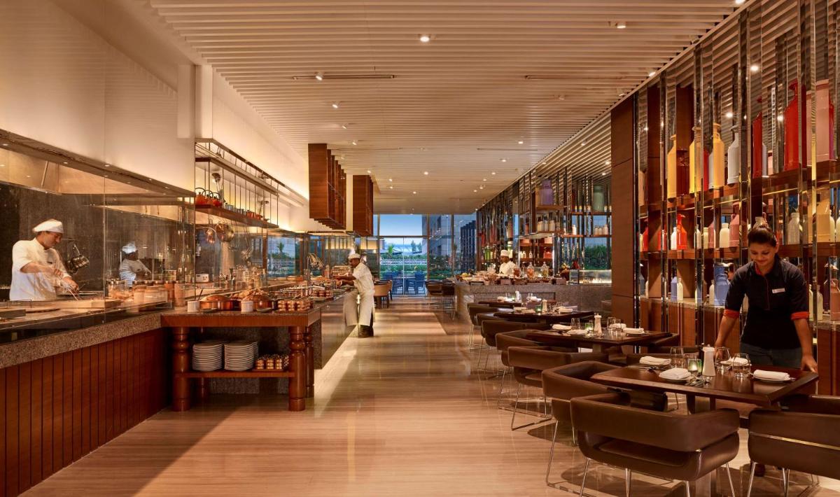 a restaurant with tables and chairs and a chef preparing food at Hyatt Regency Chandigarh in Chandīgarh