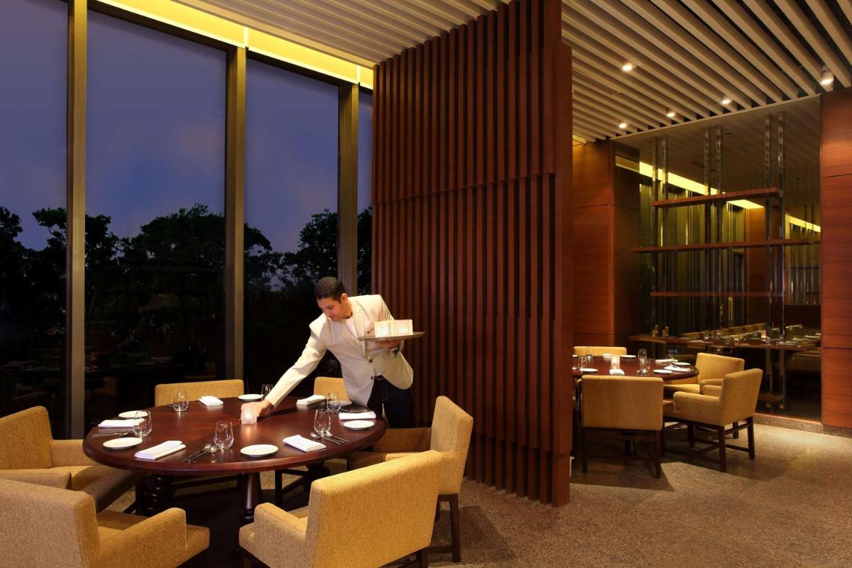 a man is standing at a table in a restaurant at Hyatt Regency Chandigarh in Chandīgarh