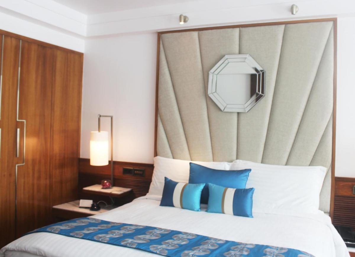 a bedroom with a bed with blue and white pillows at InterContinental Marine Drive Mumbai by IHG in Mumbai