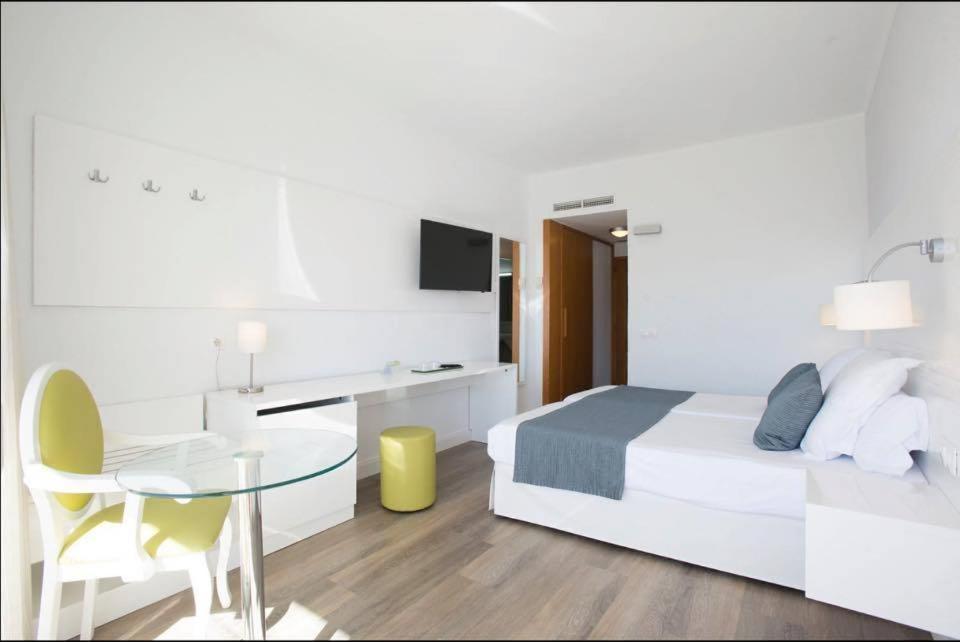 Un dormitorio con una cama, un escritorio y una mesa. en Hotel Morito, en Cala Millor
