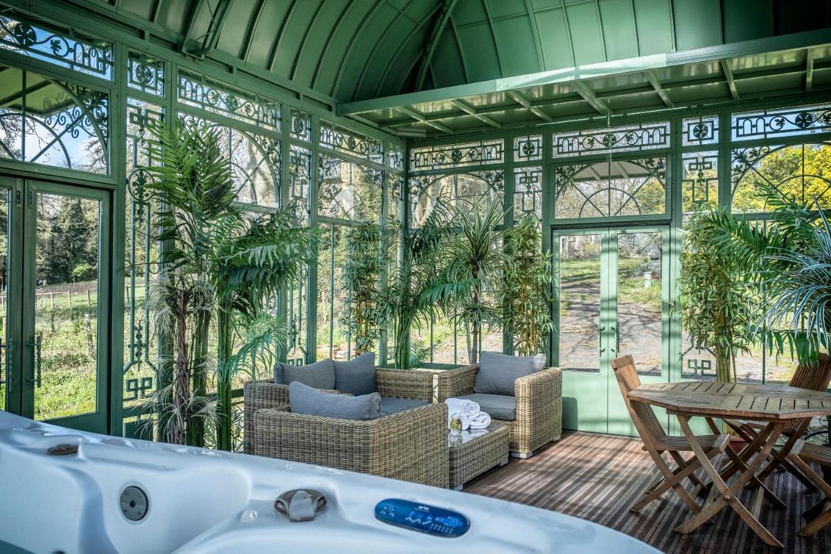 une véranda avec une baignoire, une table et des chaises dans l'établissement Château de Tressé, à Pouancé