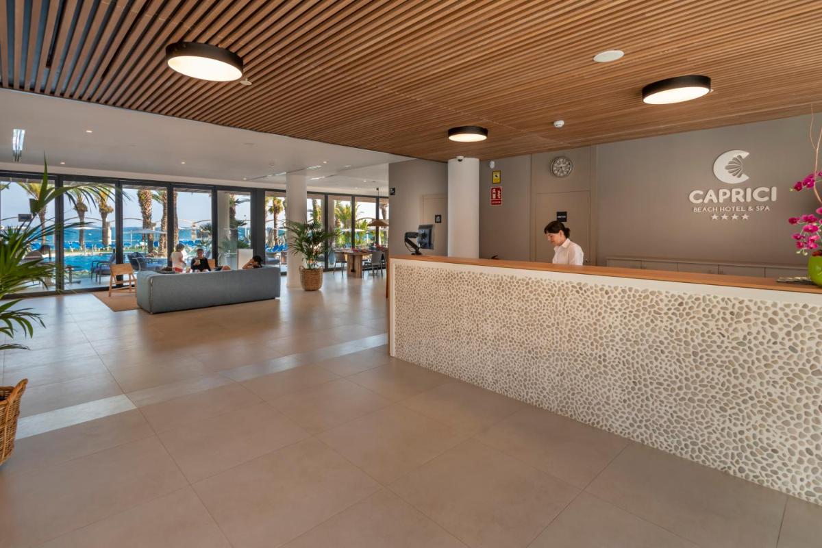 Un vestíbulo de un hotel con un mostrador de recepción. en Caprici Beach Hotel & Spa, en Santa Susanna