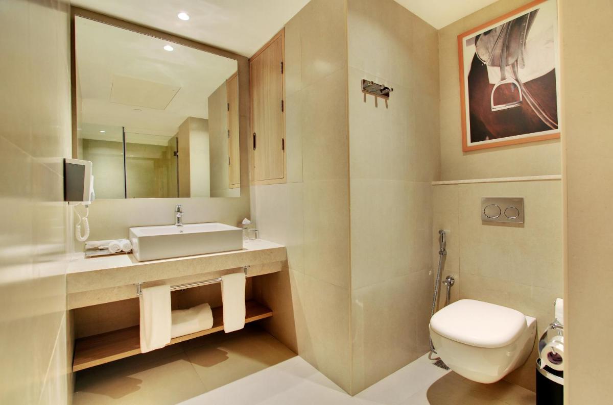 a bathroom with a toilet and a sink and a mirror at Holiday Inn Bengaluru Racecourse by IHG in Bengaluru a bathroom with a toilet and a sink and a mirror at Holiday Inn Bengaluru Racecourse by IHG in Bengaluru