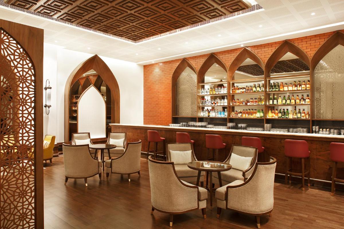 a restaurant with tables and chairs and a bar at Taj Mahal Lucknow in Lucknow