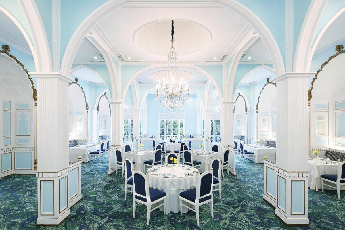a dining room with white tables and chairs and a chandelier at Taj Mahal Lucknow in Lucknow