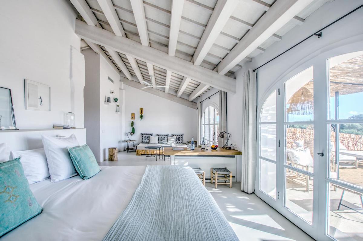 Un dormitorio blanco con una cama grande y una mesa. en Torre Vella Fontenille Menorca, en Son Bou