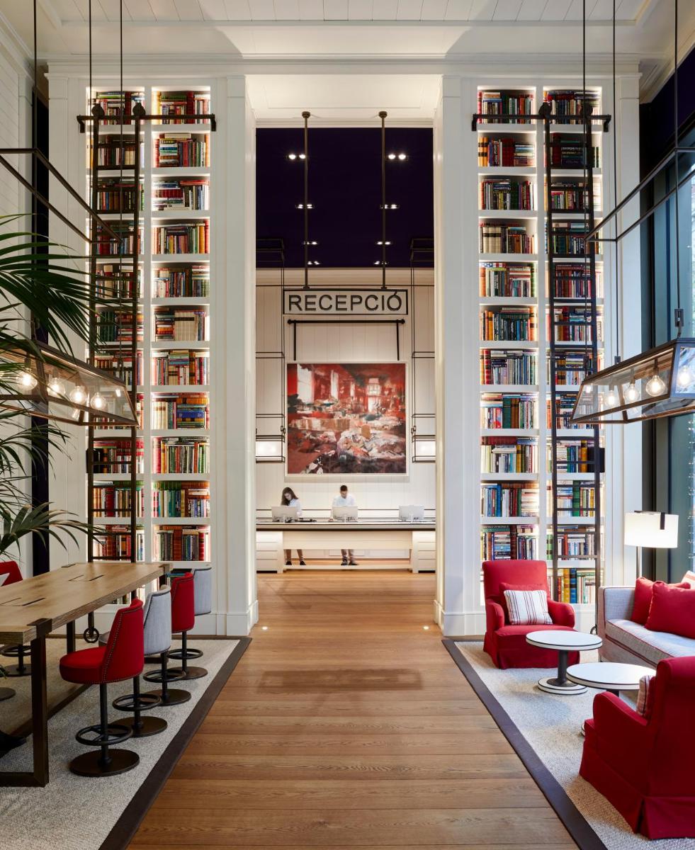 biblioteca con sillas rojas, mesa y estanterías en Seventy Barcelona, en Barcelona