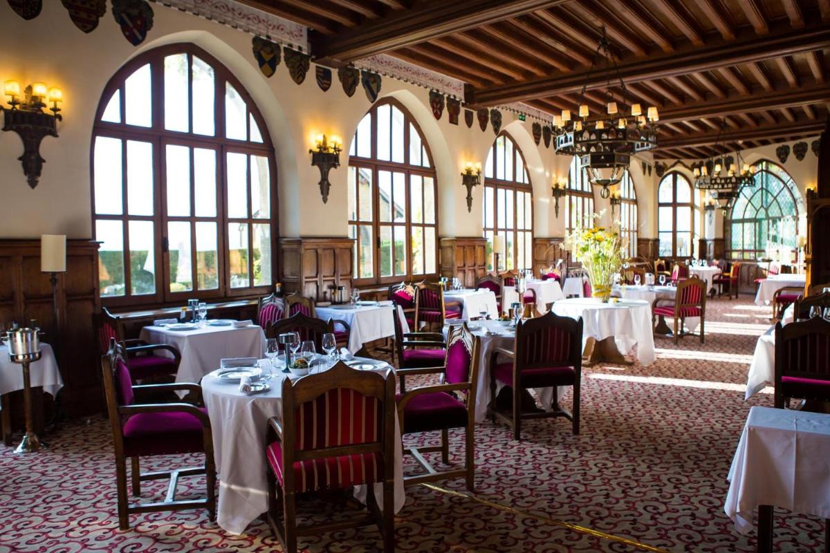une salle à manger avec des tables et des chaises blanches dans l'établissement Hotel de la Cité Carcassonne - MGallery Collection, à Carcassonne