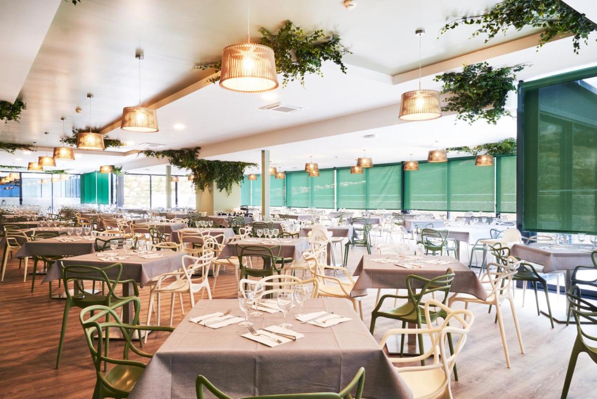 uma sala de jantar com mesas, cadeiras e luzes em RR Alvor Baía Resort em Alvor